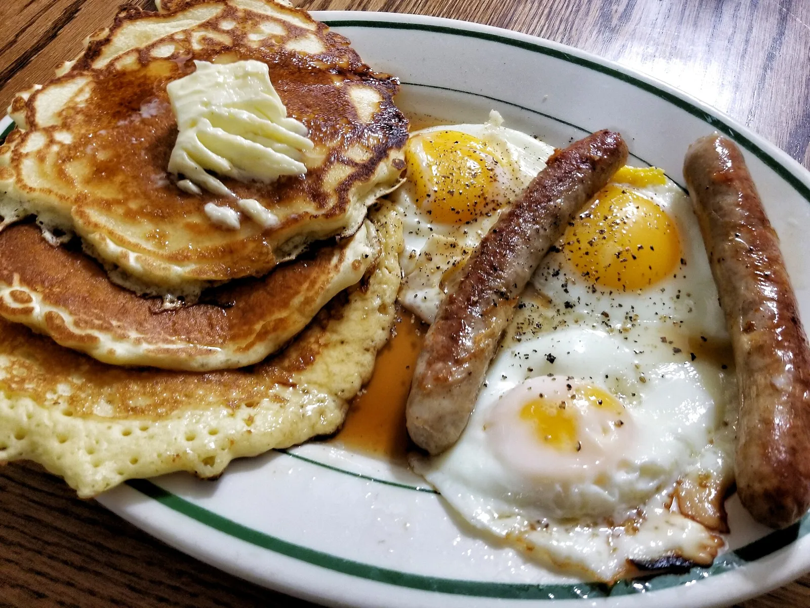 A breakfast plate of pancakes, sausage and a fried egg.