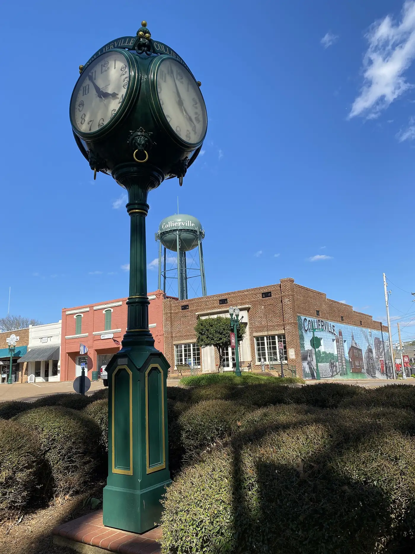 The green post clock on the Collierville Town Square, with the town water tower behind it.