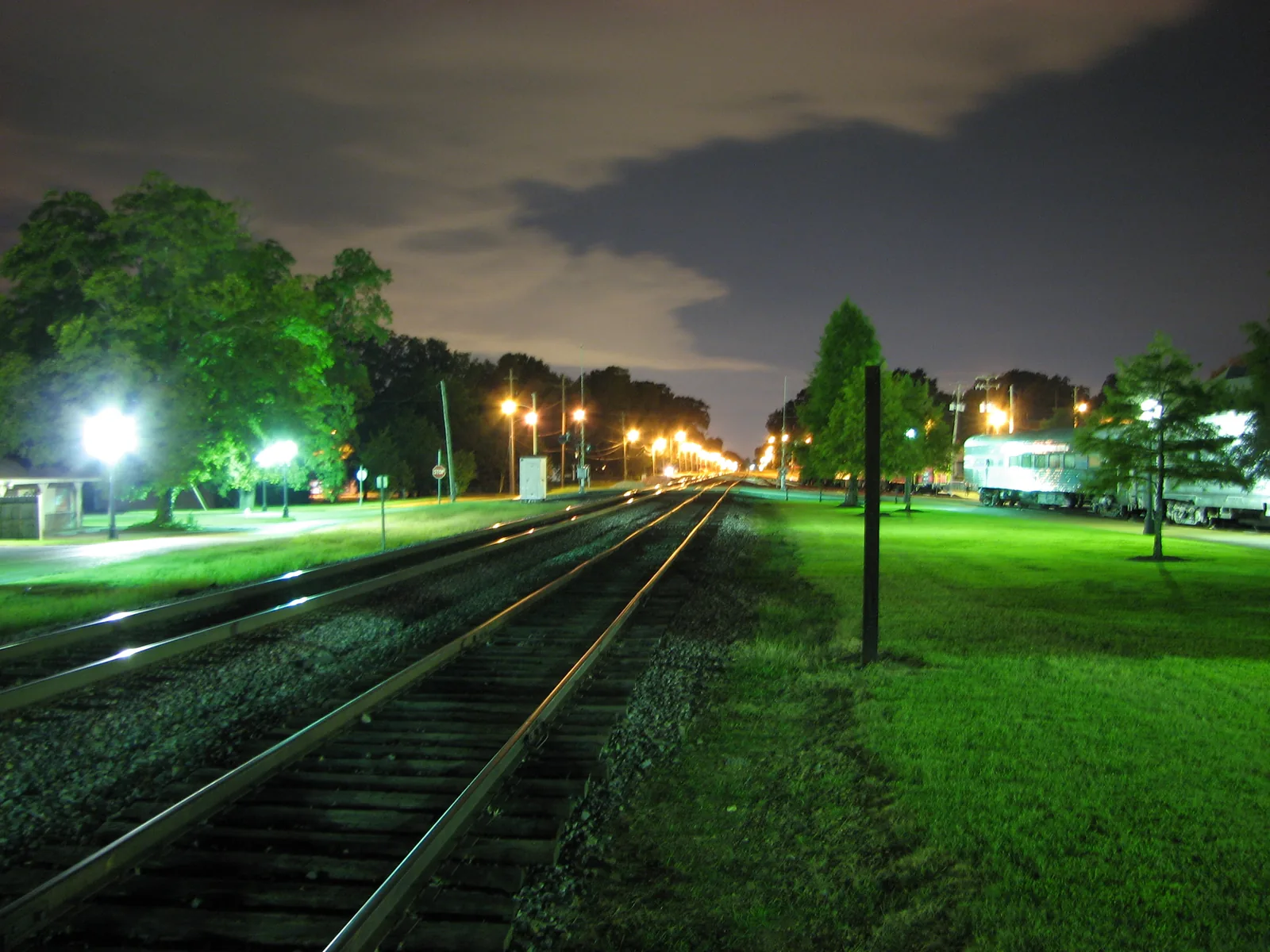 Lamps light the railroad and the depot grounds beside the Collierville Town Square at night.