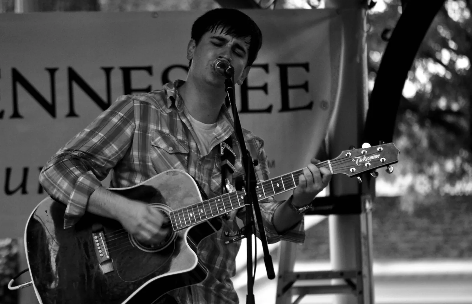 A singer-songwriter performs with an acoustic guitar at an outdoor show in Collierville.