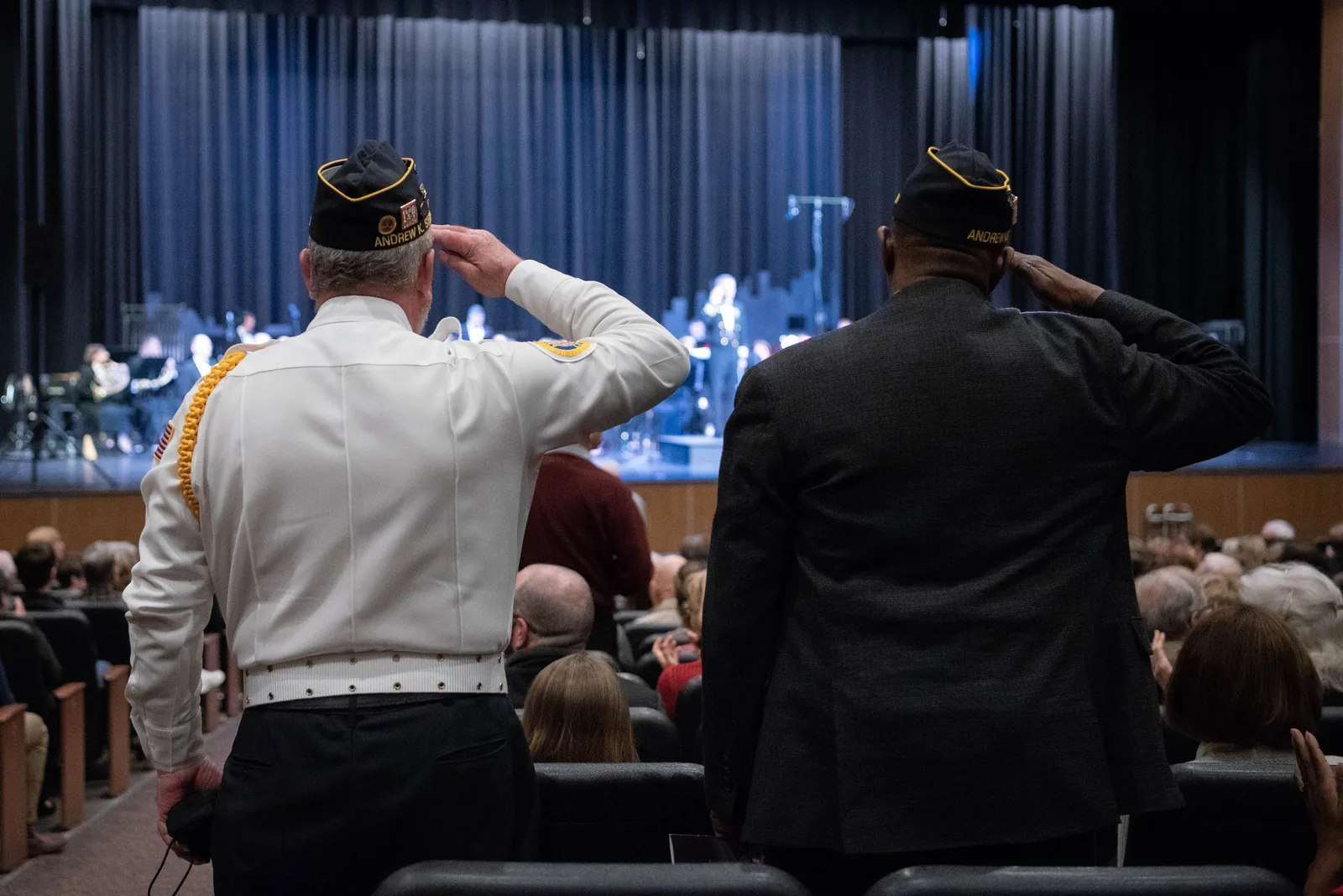 Army veterans stand and salute as their service song plays during a U.S. Navy Band concert at Pickler Auditorium in Collierville.