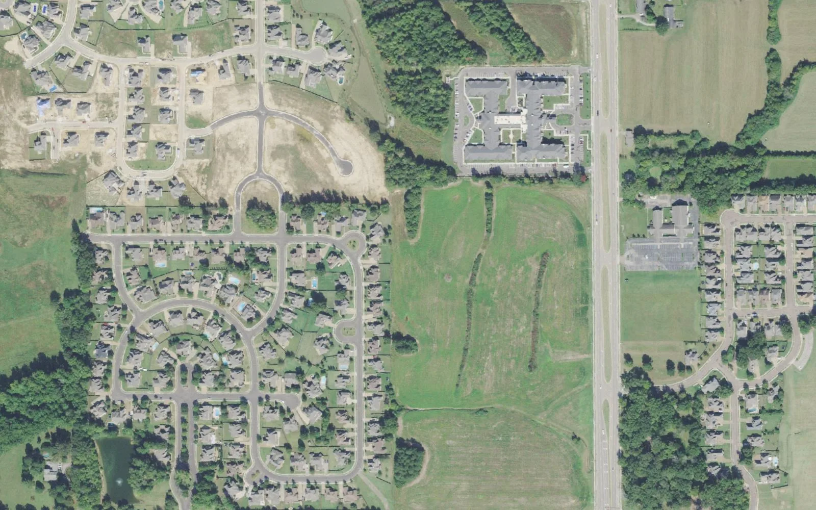 Oak Grove in Collierville from the air: finished streets of homes, new lots under construction and an apartment complex beside an open field